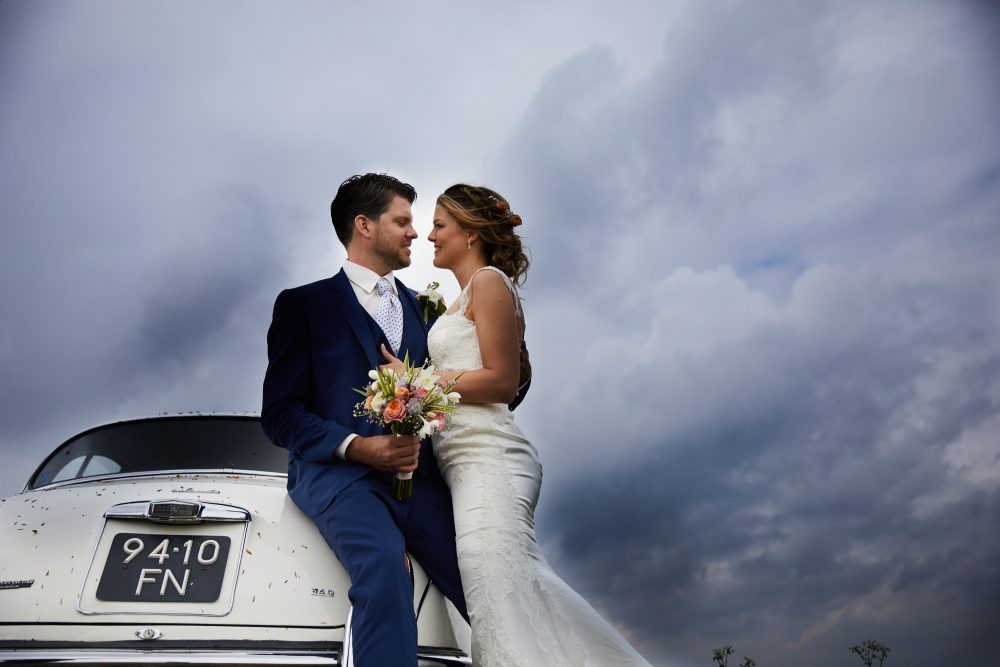 Bruidsfotografie met trouwauto en bruidspaar